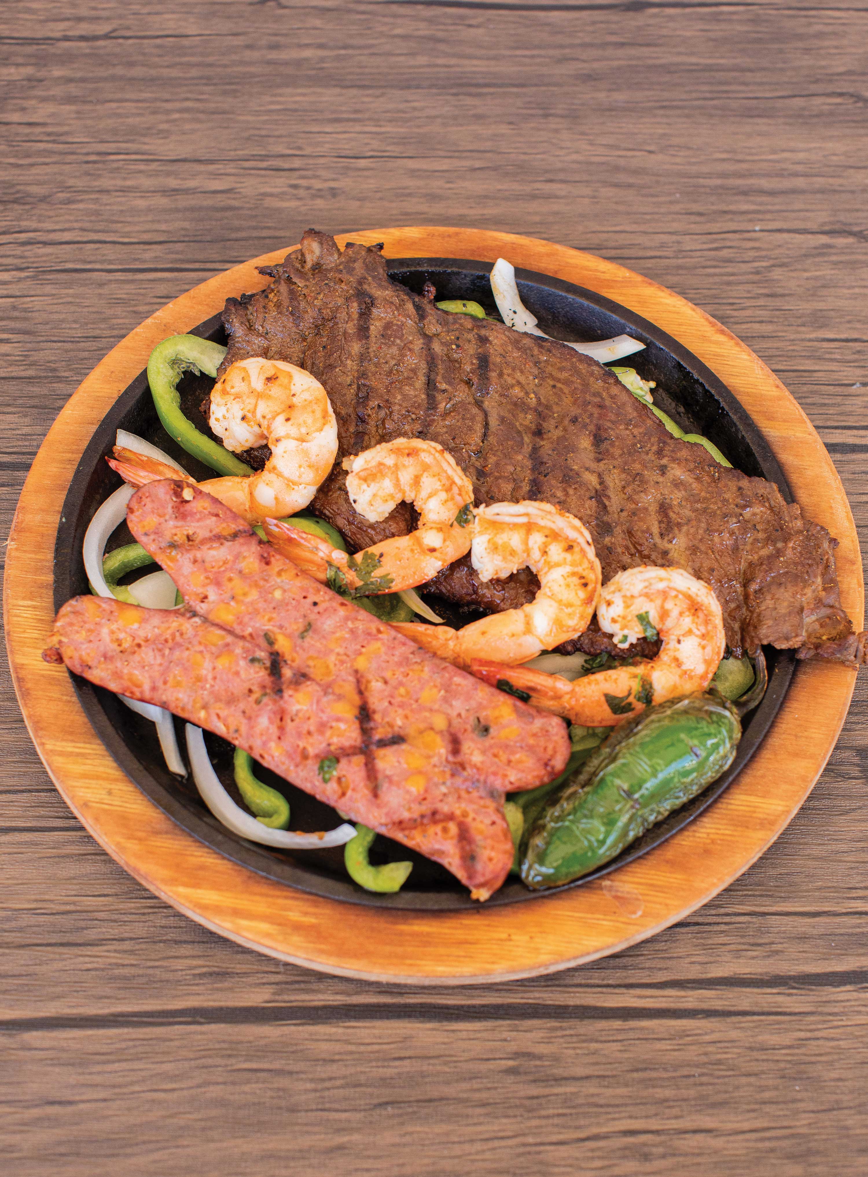 Image: Grilled steak displayed alongside a halved chorizo sausage and 4 grilled shrimp.