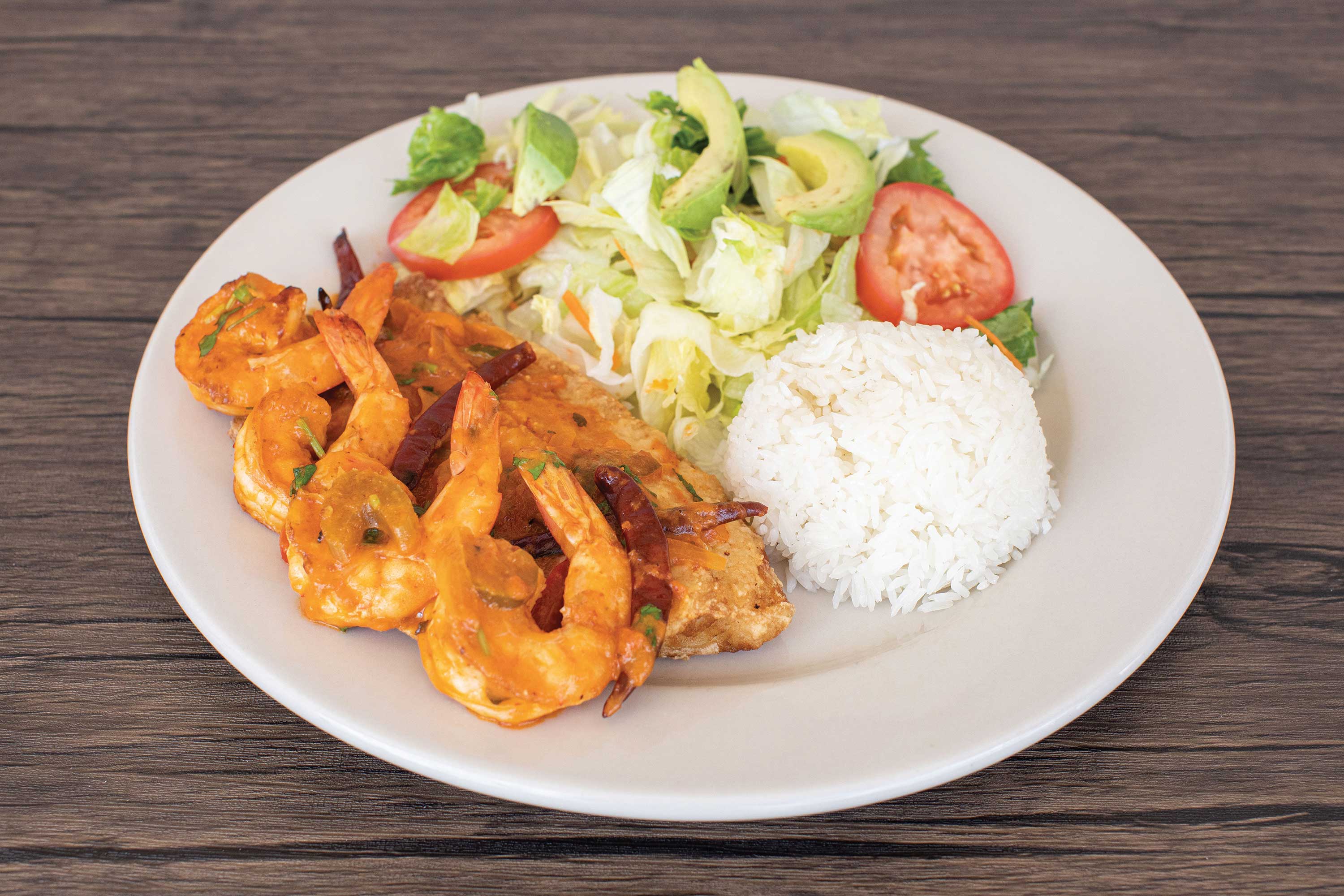Image: Tilapa fish fillet topped with grilled shrimp alongside a lettuce and tomato salad with a mound of white rice.